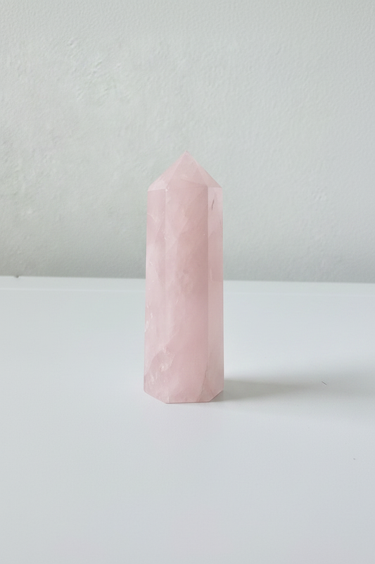 Punta de cuarzo rosa natural sobre fondo blanco